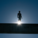 silhoutte of man on bridge with rising sun behind him