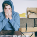 man sitting on sofa with hands covering face