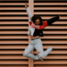Woman jumping in the air in front of a brown slatted door