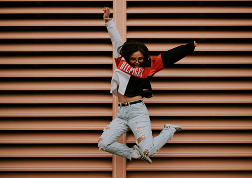 Woman jumping in the air in front of a brown slatted door